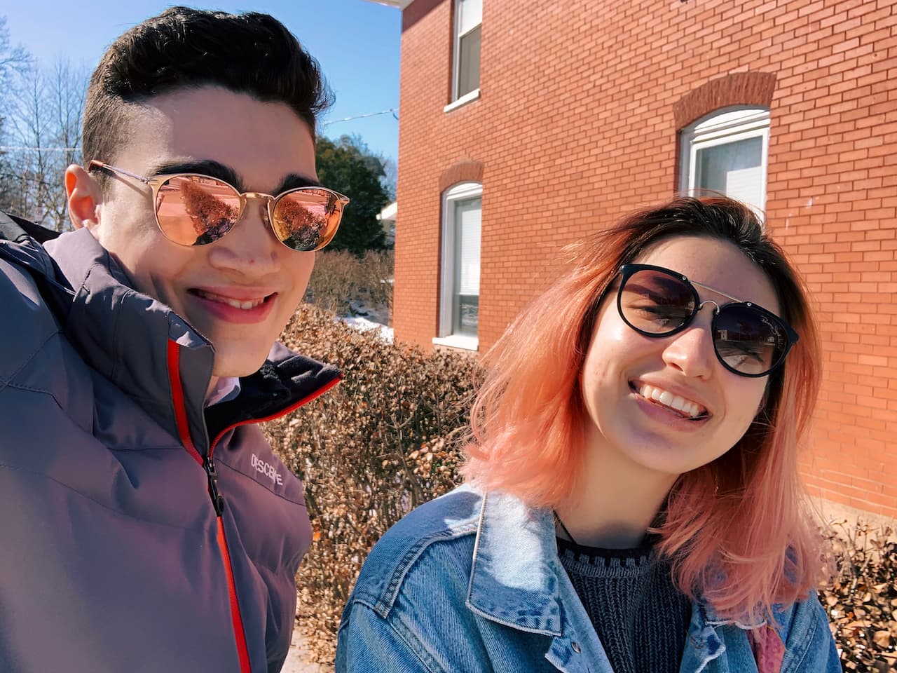 Lachlan & friend posing with colorful sunglasses against a snowy building