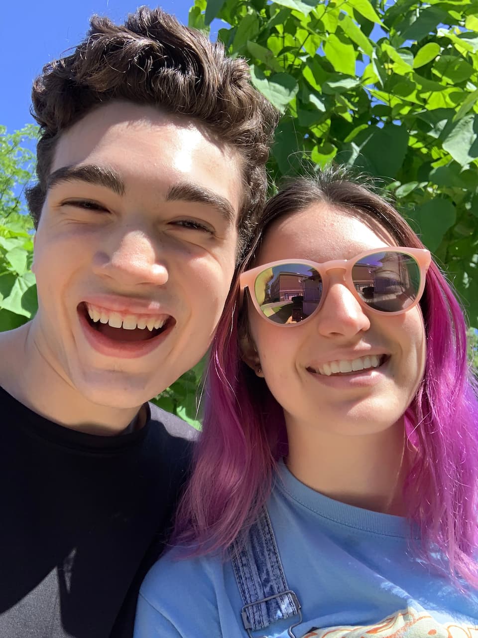 Happy Lachlan & same friend posing in a dress & overalls respectively in front of a tree